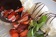 Dessert-Traum aus raffiniertem Schokobecher mit erntefrischen Erdbeeren, Minze und Vanilleeis im Wirtshaus Neuhof.