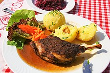 Knusprig gebratene Entenkeulle mit hausgemachten Kartoffelknödeln im winterlichen Wirtshaus Zenting.