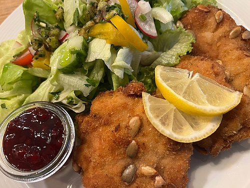 Frisch zubereitetes, knusprig paniertes Kürbiskernschnitzel  mit Wildpreiselbeeren und buntem Beilagensalat im Landhotel Neuhof